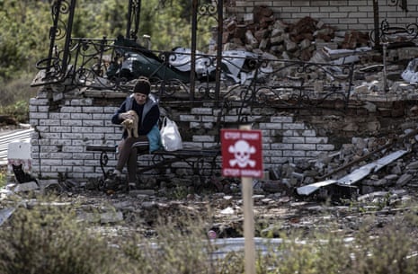 A woman pets a cat in the ruins of a damaged house in Dalin village in Kharkiv.