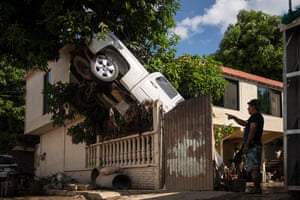 A pickup truck hangs over a fence outside a house