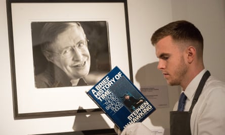 An auctioneer assistant reads late physicist Stephen Hawking’s seminal works.