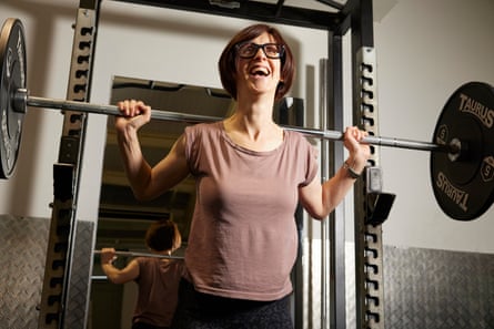 Emma Beddington laughing while holding a huge barbell