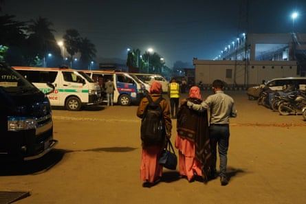 Two women and a man walk across a carpark