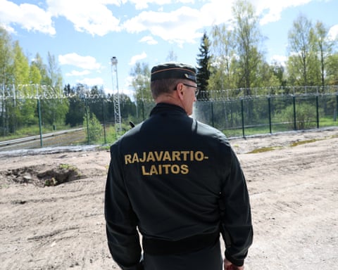 Rear of a border guard standing in front of the fence on the Finnish-Russian border
