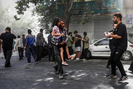 A man carries a wounded girl after an explosion in downtown Tehran, Iran, on 15 June after an Israeli strike.
