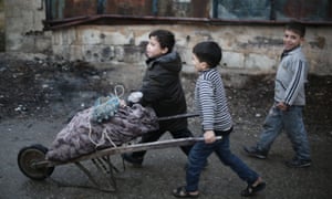 Children push a barrow filled with firewood in Ghouta, Syria