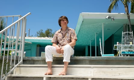 Paul Dano as Brian Wilson sits on steps near swimming pool