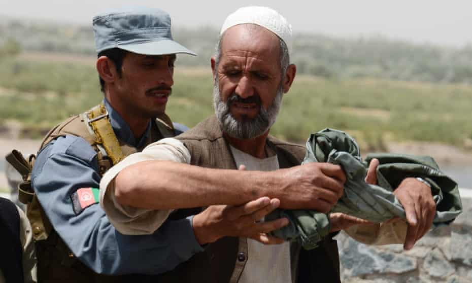 An Afghan policeman searches a man at a checkpoint in Herat province