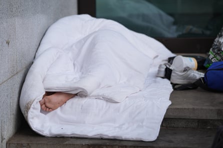 A person wrapped in a duvet lies on the steps of a court building