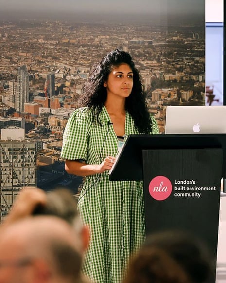 Amanprit Arnold speaks at a podium beside a laptop and projector screen