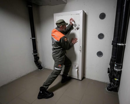 A man in a uniform closes a heavy door
