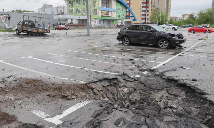 A crater and damaged cars left by shelling in Kharkiv.