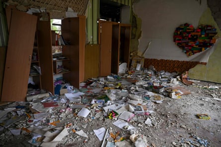Books and other debris lie strewn across a classroom in Izuim, Ukraine