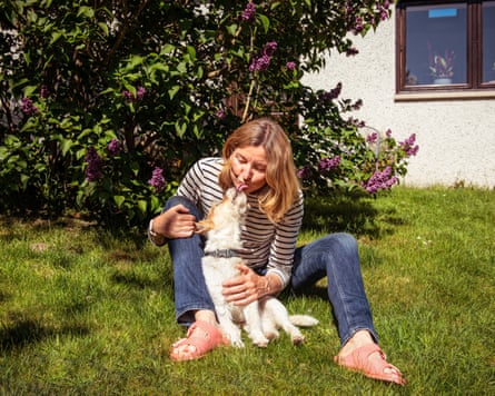 Sam Pyrah with her dog Morris, sitting in a garden, Morris is licking her face