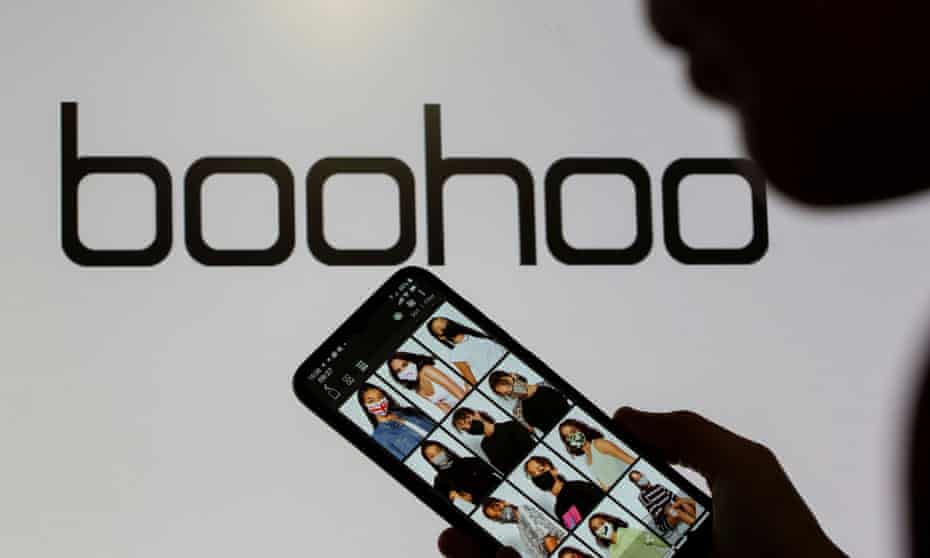 A woman poses with a smartphone showing the Boohoo app