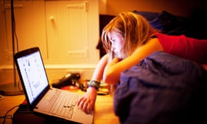 a 12 twelve 13 thirteen year old teenage girl on bed in her bedroom at night reading Facebook page on laptop computer UK