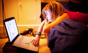 teenage girl in her bedroom reading Facebook page on laptop computer UK
