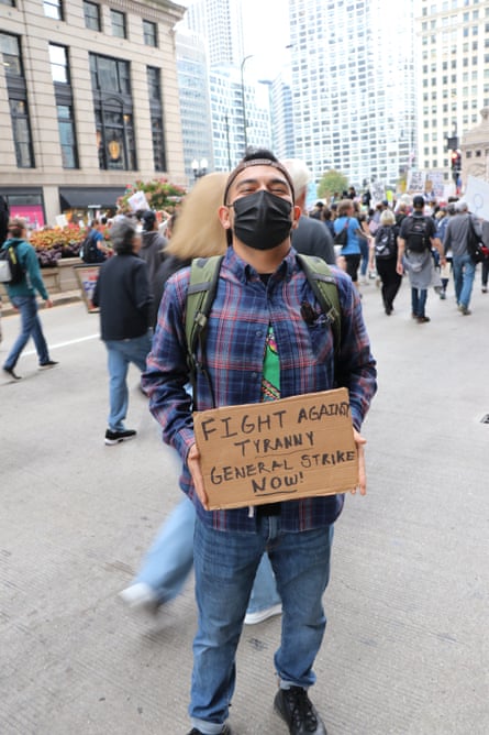 man outside at prtoest holds up a sign saying ‘fight against tyranny / general strike now!’