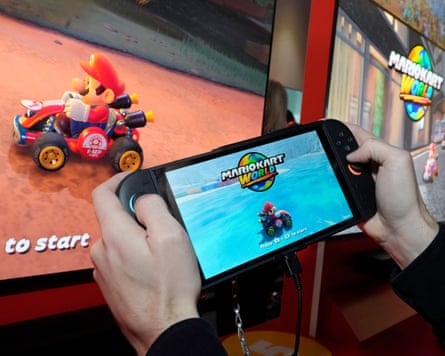 A person holding a Nintendo Switch console playing Mario Kart.