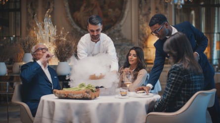 Eva Longoria, Alain Ducasse and Lindsey Tramuta sit in an elegant restaurant while a chef and waiter serve them