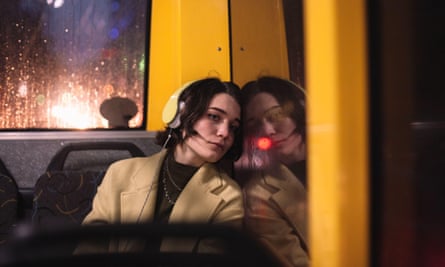 Young woman wearing headphones, looking through window travelling on a bus