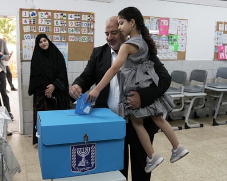 Mansour Abbas, holding his daughter, places a ballot into a voting box