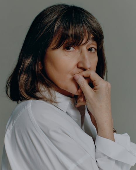 Beeban Kidron with a dark long bob haircut and wearing a crisp white shirt, rests her hand near her mouth, looking at the camera