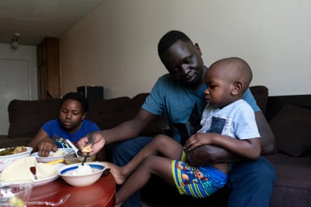 Okello feeds his son Ezekiel dinner at his apartment.