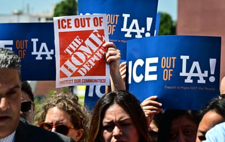 people hold up signs outside such as ‘ice out of LA’ and ‘ice out of the home depot / protect our communities’