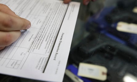 A white hand fills out a print-out that says at the top ‘Firearms Transaction Record’.