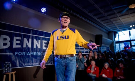 man giving a speech wearing a yellow shirt reading LSU