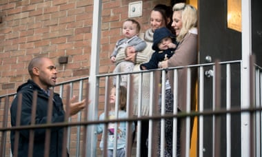 Rees talks to mothers outside the laundry room of a block of flats.
