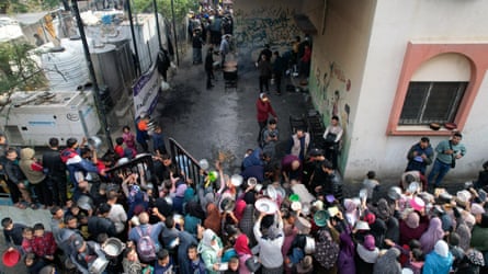 Palestinians gather to receive food cooked by a charity kitchen in Rafah