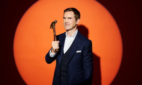 Jimmy Carr holding a hammer.