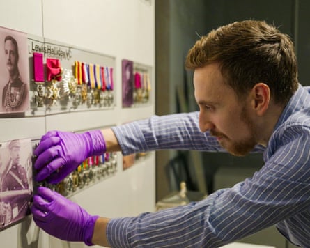 Berry, wearing purple gloves, installs medals on an exhibition wall display