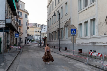 A woman walking through a closed street with damaged buildings