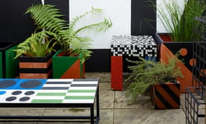 A patchwork of different colours and shapes on big square plant pots and a table in the garden.