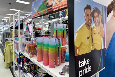 Shelves of rainbow colored plastic cups, and a sign that shows two people hugging that says Take Pride.