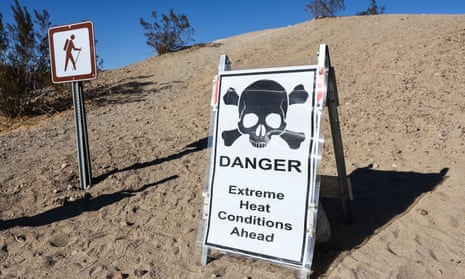 A sign on a sandy dune reads 'Danger: Extreme heat conditions ahead' with an image of a skull and crossbones above.