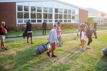 Migrants wheel suitcases outside school in Martha’s vineyard.