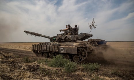 Ukrainian servicemen ride atop a tank near a front line in Mykolaiv region