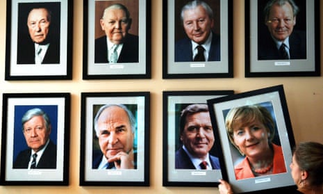 A portrait of the German chancellor Angela Merkel is added to a wall featuring pictures of her predecessors