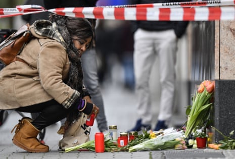 A woman sets a candle near the scene where several people were killed in Hanau, Germany, 20 February