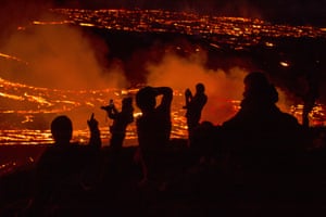 People watch as lava flows from an eruption of a volcano on the Reykjanes peninsula.