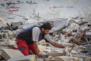 Aljaleel rescues a cat from the rubble of a bombed area of Khan Sheikhun as he searches for surviving felines to take to his sanctuary