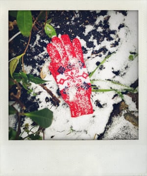 A red child’d winter glove covered in snow in London garden 08-02-2021. All through the long quarantined winter, they called