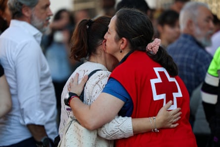 A member of the Spanish Red Cross, in a red vest with a white cross on the back, embraces a woman as they wait for news of passengers on the two high-speed trains that collided near Urda.