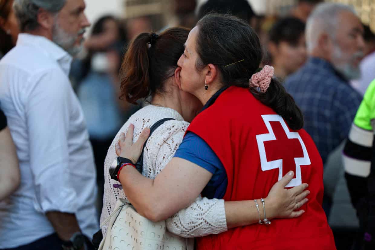 A member of the Spanish Red Cross, in a red vest with a white cross on the back, embraces a woman as they wait for news of passengers on the two high-speed trains that collided near Urda.