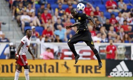 Columbus Crew defender Jonathan Mensah heads the ball in front of New York Red Bulls midfielder Derrick Etienne.