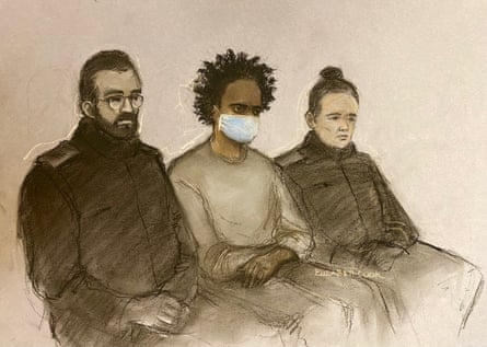 Sketch of Rudakubana in a face mask, sitting between two officers