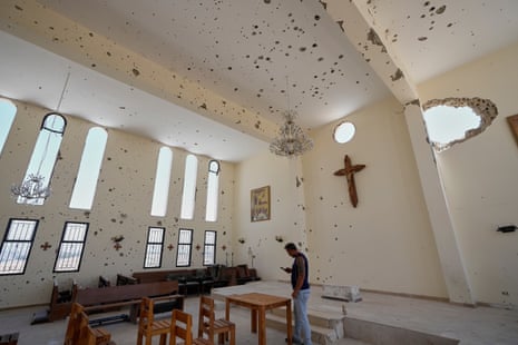 A man stands inside a damaged church.