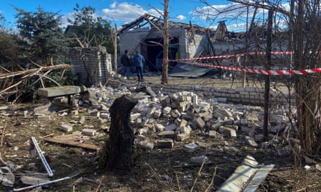 Local men stand next to residential buildings damaged by a Russian missile strike, in the village Obukhivka, in the Dnipropetrovsk region.